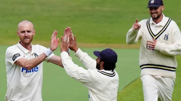 Olly Hannon-Dalby is given a double 'high five' by a team-mate after taking a wicket for Warwickshire